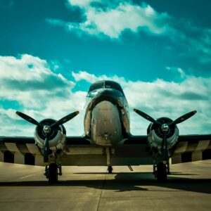 Front view of a classic military aircraft on a runway under a clear blue sky.